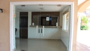Entrada com porta de vidro, balcão de recepção e sinalização indicando aceitação de Visa.