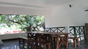 Una mesa de madera y bancos en una habitación con vistas a árboles y un edificio.