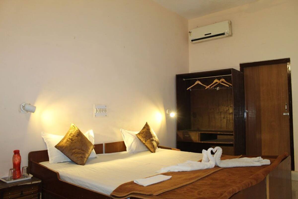 Ein Hotelzimmer mit Bett, Kissen, einem Holzschrank und einem Handtuchhalter.