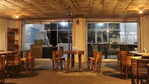 Un comedor interior con mesas y sillas de madera, ventanas amplias y un techo con diseño de cuadrícula.