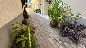 A narrow corridor with a tiled floor, potted plants, and a blue awning.