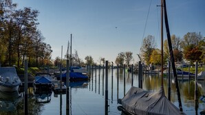 Un port de plaisance avec des bateaux amarrés, une eau calme et des arbres en arrière-plan.