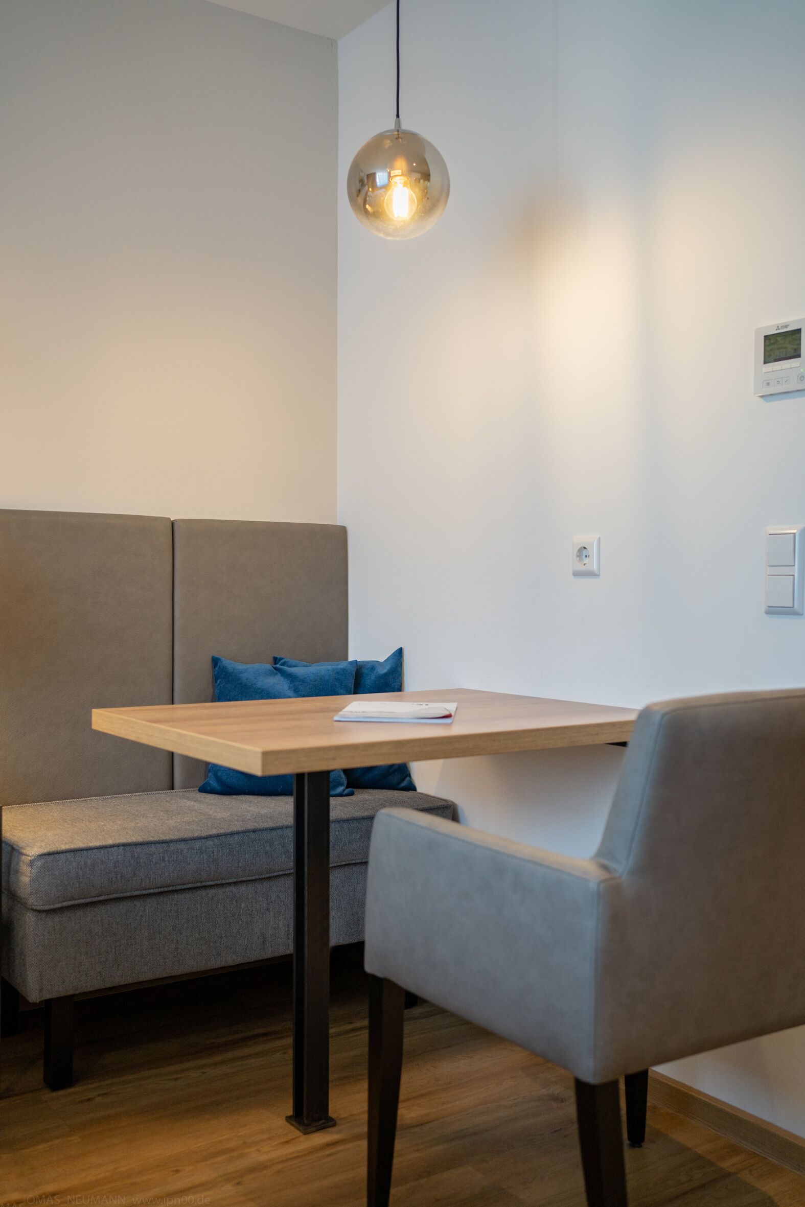 A modern room with a wooden table, a grey sofa, and a blue cushion.