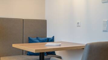 A modern room with a wooden table, a grey sofa, and a blue cushion.