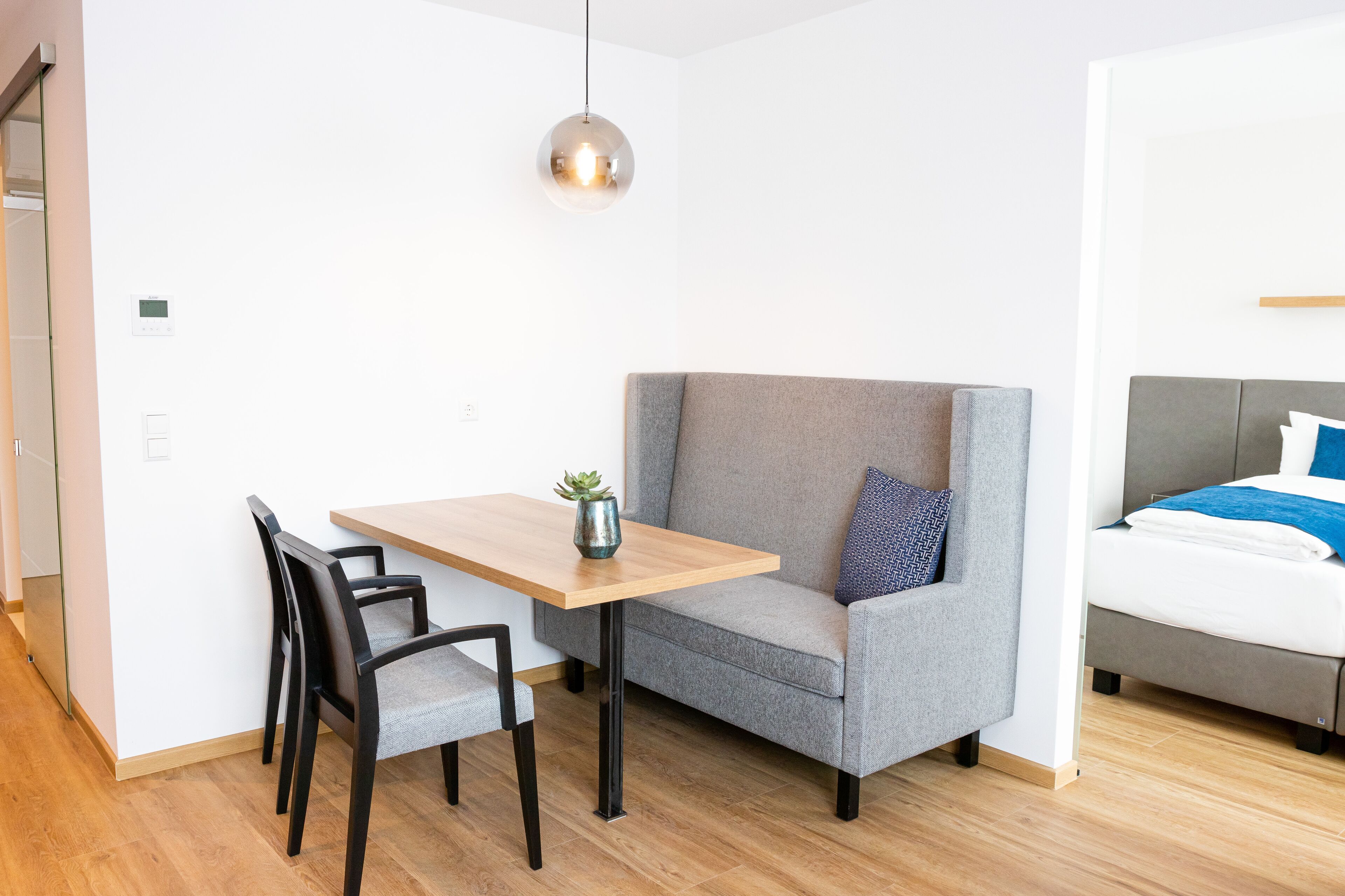Una habitación moderna con un sofá gris, una mesa de madera y una pequeña planta.