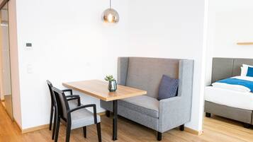 Una habitación moderna con un sofá gris, una mesa de madera y una pequeña planta.
