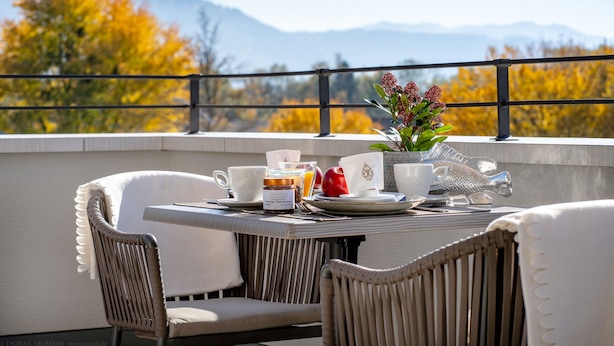 Une table à manger avec des chaises, un vase rempli de fleurs et une vue imprenable sur les montagnes.