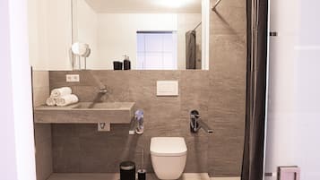 Une salle de bain moderne équipée d’un lavabo, d’un miroir, de toilettes et d’une douche.