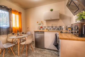 Enjoy cooking and dining in this compact kitchen with a central island, appliances, and a dining area with a table and chairs.