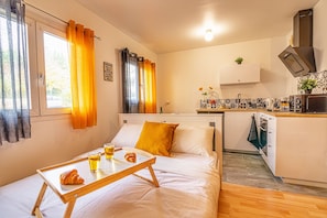 Cozy retreat with a bed, kitchenette, and table for a comfortable stay.