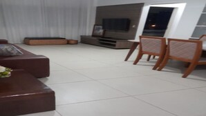 Un soggiorno con divano, televisore e zona pranzo con sedie.