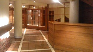 A corridor with tiled flooring, wooden paneling, and a reception desk.