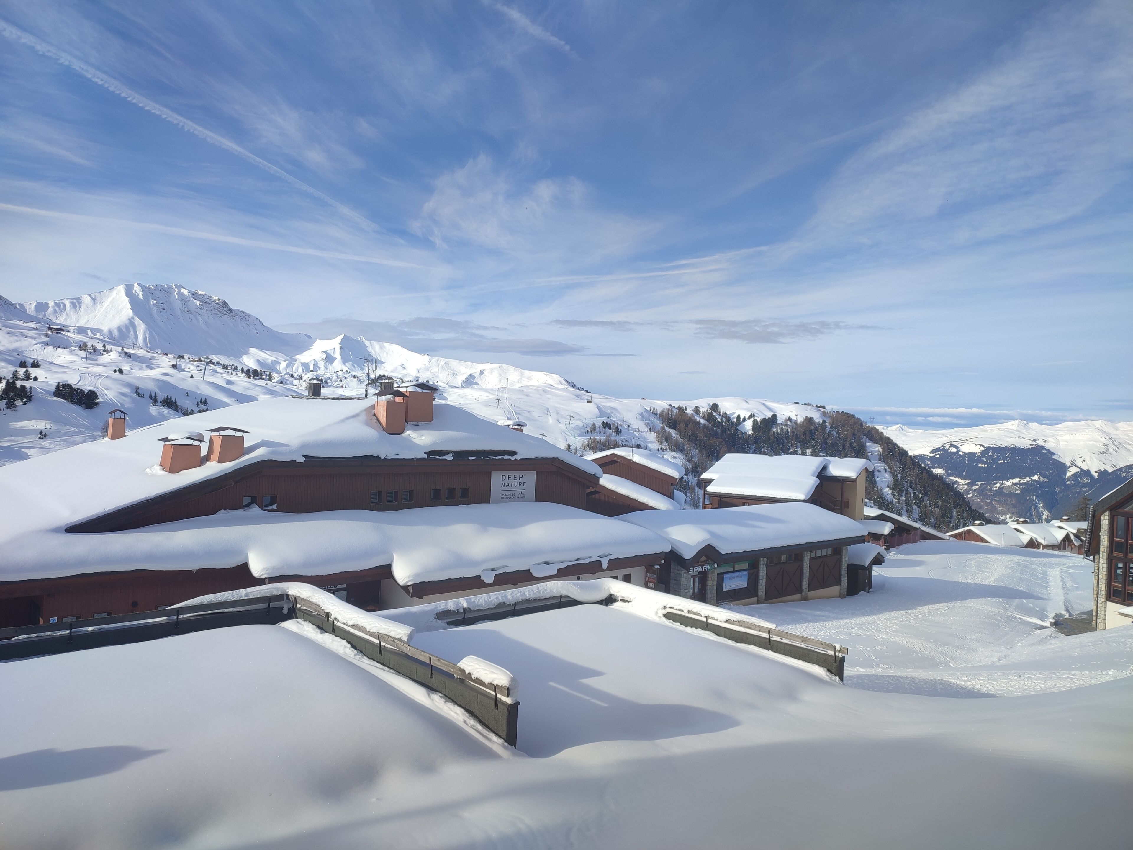 A snow-covered mountain village with traditional chalet-style buildings, a ski lift, and a clear view of the surrounding mountains.