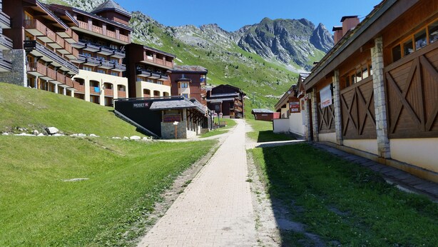 A mountain lodge with multiple balconies, a ski lift, and a path leading to the entrance.