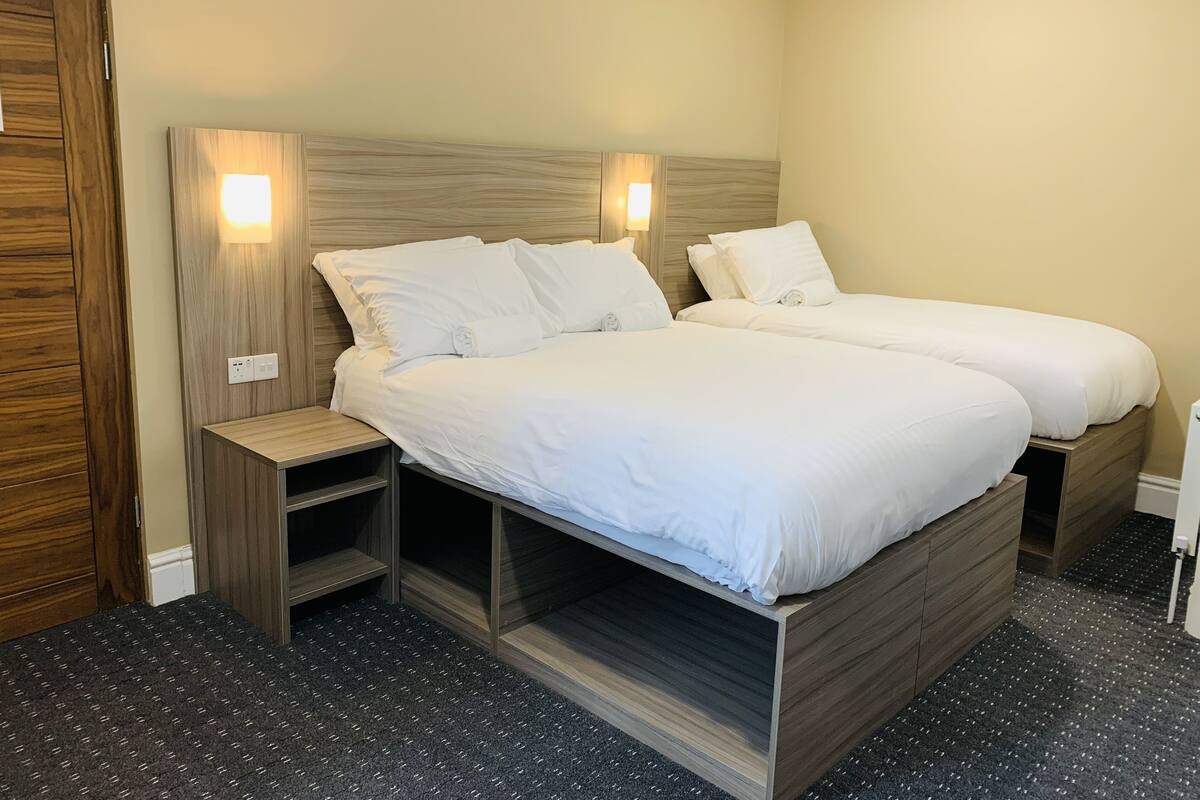 Una cama doble con cabecera de madera, dos mesitas de noche y suelo alfombrado.