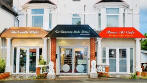 A building with three storefronts: The Candle Night Fine Indian Cuisine, De Regency Style Hotel, and Room 101 Cafe. - De Regency Style Hotel (Redditch)