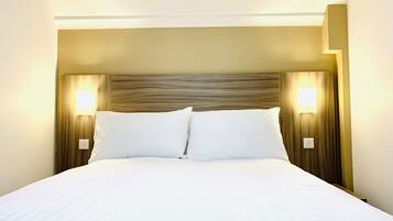 Habitación de hotel con una cama grande, dos lámparas de noche y un cabecero de madera.