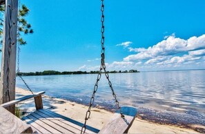 Relax on a serene beach with a wooden swing set overlooking the calm waters.