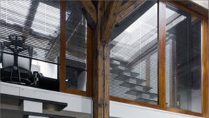 Ein modernes Interieur mit einer Holztreppe, einem Essbereich und einem großen Fenster.