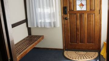 A wooden door with a stained glass window, a bench, and a mat at the entrance.