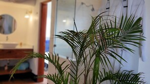 Een badkamer met een potplant, een spiegel en een handdoekrek.