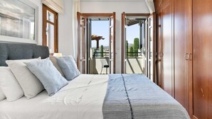 A bedroom with a bed, pillows, a bedside table, and a view of the outside balcony. - Apartment DD12 - Chloe (Kouklia)