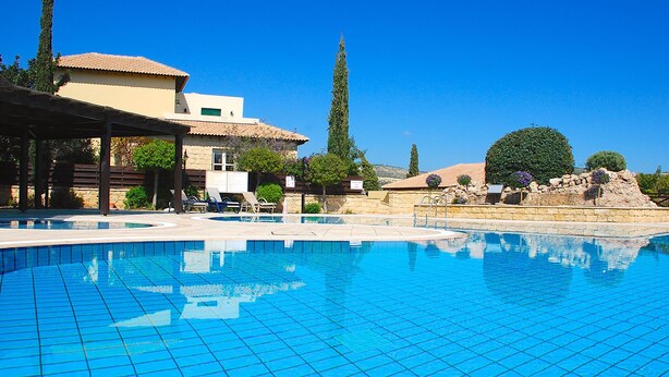 A swimming pool with lounge chairs and a building with a tiled roof. - Apartment U3 - Avdimou (Kouklia)