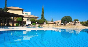 A swimming pool with lounge chairs and a building with a tiled roof. - Apartment U3 - Avdimou (Kouklia)