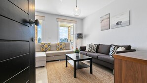 A modern living room with a sofa, coffee table, and a view of the city through large windows. - Apartment U3 - Avdimou (Kouklia)