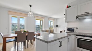A modern kitchen with white cabinets, a granite countertop, a built-in microwave, and a stainless steel range hood. - Apartment U3 - Avdimou (Kouklia)