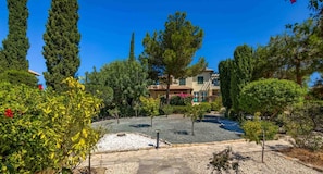 Un patio con un edificio, rodeado de árboles y un camino de grava.