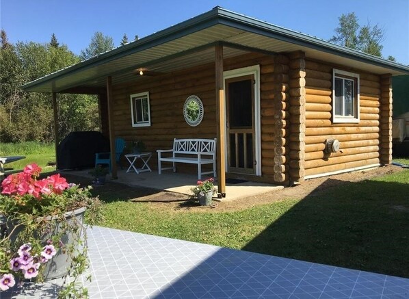 Cozy cabin with a front door, window, and covered porch, perfect for relaxation.