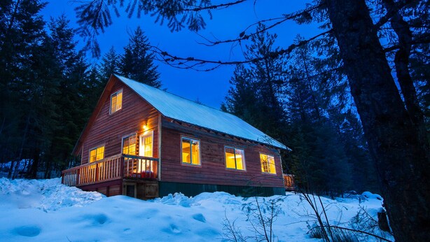 A log cabin with a metal roof, surrounded by snow and trees. - Quiet & comfortable guest house on 20 acre ranch (careywood)