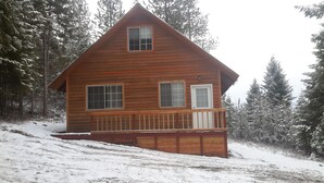 A wooden cabin with a balcony, surrounded by snow-covered trees. - Quiet & comfortable guest house on 20 acre ranch (careywood)