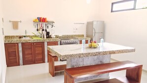 A kitchen with granite countertops, wooden cabinets, a built-in stove, and a bench.