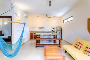 A modern interior with a hammock, a sofa, a wooden bench, a kitchen area, and a ceiling fan. - Secluded apartment with the best location in Tulum Town (Centro)
