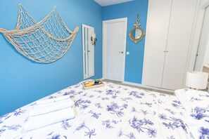 A bedroom with a bed, a blue wall, a white door, and a wardrobe.