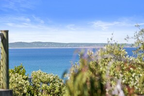 A coastal view with a clear sky, a body of water, and distant land. - Silver Birches - Stroll To Town (Lorne)