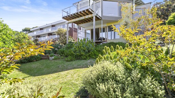 A modern two-story house with a covered outdoor area and a well-maintained garden.