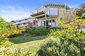 Ein modernes, zweistöckiges Haus mit überdachtem Außenbereich und einem gepflegten Garten.