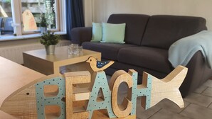 Une décoration en bois sur le thème de la plage, avec le mot « PLAGE » inscrit dessus, posée sur une table dans un salon.
