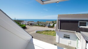 Un quartier résidentiel offrant une vue dégagée sur la mer, des maisons dotées de panneaux solaires et une pelouse bien entretenue.
