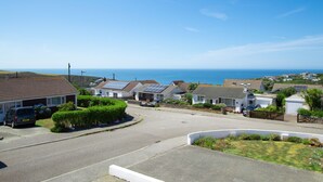 Une zone résidentielle côtière avec des maisons, un ciel dégagé et la mer en arrière-plan.
