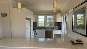 A modern kitchen with a central island, bar stools, a refrigerator, microwave, and a dishwasher. - McCrae: location, location! Boasting  bay views with the beach a 5 minutes walk. (McCrae)