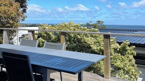 A wooden deck with a table and chairs, overlooking a body of water and a clear sky. - McCrae: location, location! Boasting  bay views with the beach a 5 minutes walk. (McCrae)