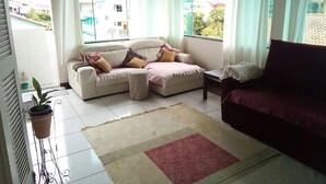 A living room with a sofa, a red couch, a small table, and a potted plant. - Beach House Great Value (Ingleses Norte)