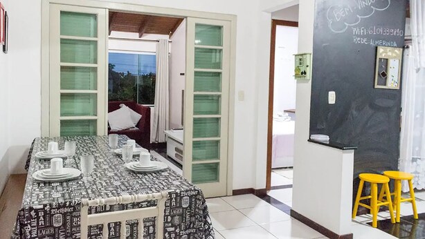 A dining area with a table set for four, a red couch, and a chalkboard with Wi-Fi details. - Beach House Great Value (Ingleses Norte)