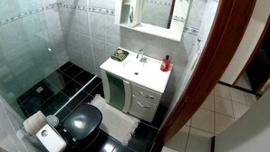 A bathroom with a toilet, sink, and mirror. - Beach House Great Value (Ingleses Norte)