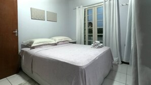 A bedroom with a bed, a window with curtains, and a door. - Beach House Great Value (Ingleses Norte)