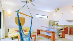 A modern living room with a hammock, a sofa, a wooden bench, a kitchen area, and a ceiling fan. - Nestled in the heart of Tulum town, steps away from Tulum's most lively street (Tulum)